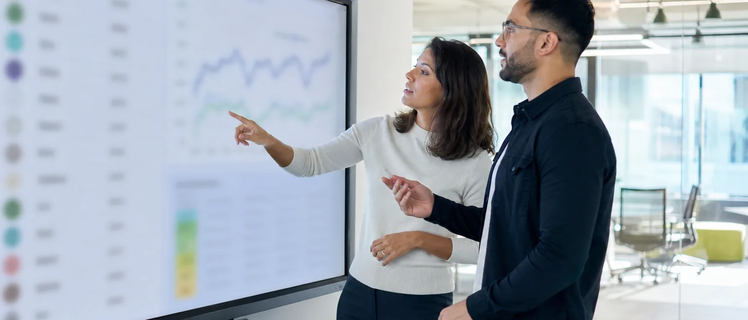 Growth marketer comparing ranking positions on a dashboard with a colleague