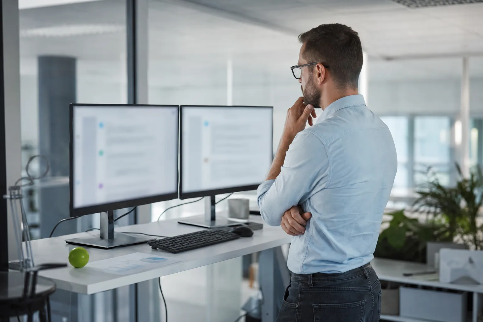 SEO lead at a standing desk comparing two AI answers on side by side monitors