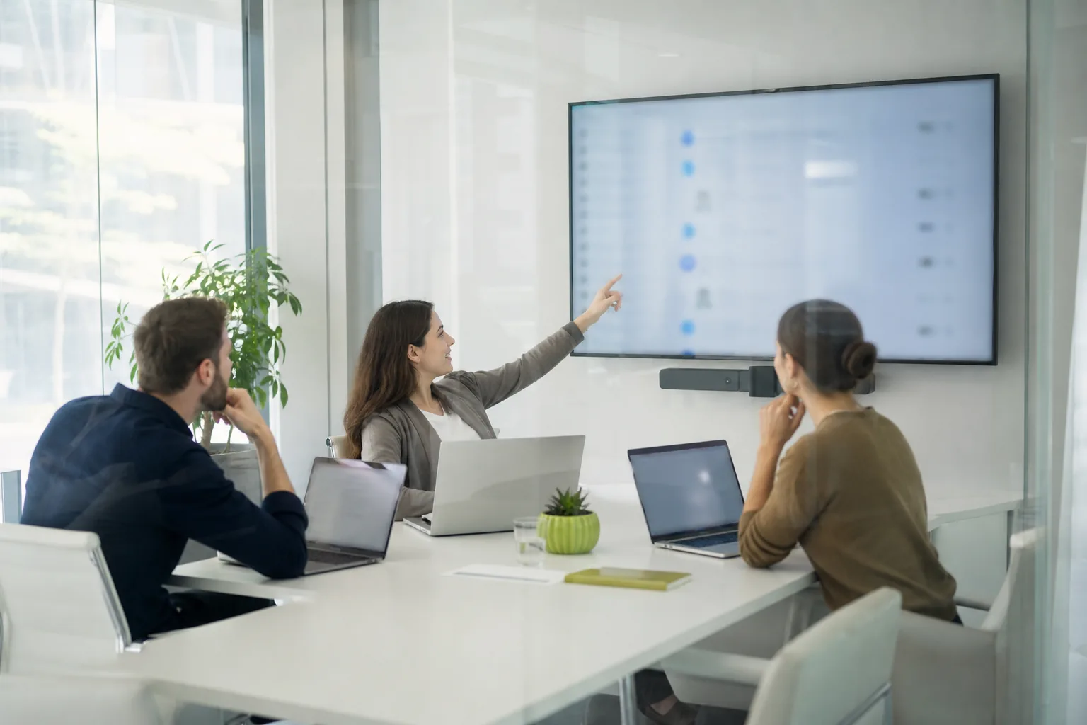 Communications team in a glass meeting room reviewing a list of mentions on a wall screen